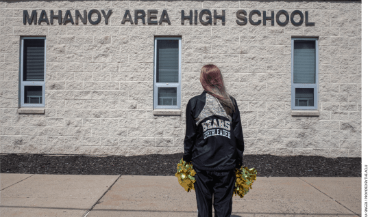 Cheerleader stands in front of Mahanoy Area High School