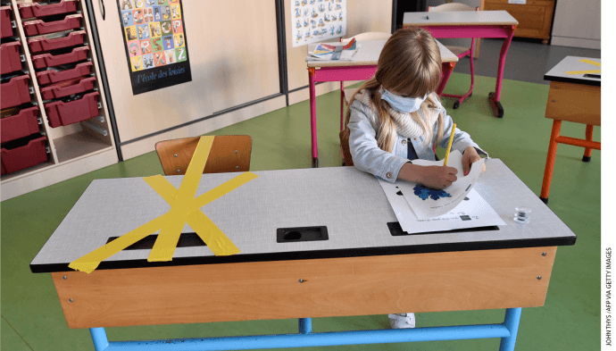 A student at the Sainte-Croix elementary school works as half of her writing desk is marked with a tape to ensure that safe distance is kepton May 15, 2020, in Hannut, Belgium.