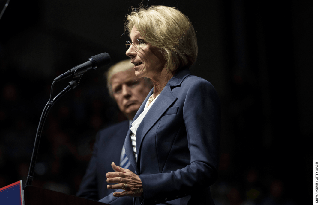 President-elect Donald Trump looks on as Betsy DeVos, his nominee for Secretary of Education, speaks at the DeltaPlex Arena, December 9, 2016 in Grand Rapids, Michigan.