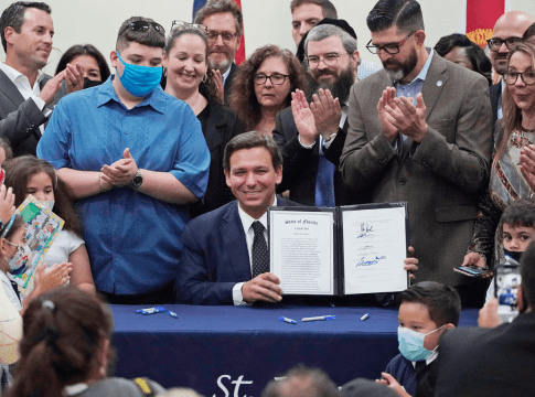 Florida Gov. Ron DeSantis, seated, celebrates after signing a bill that expands eligibility for state scholarships to fund private-school tuition.