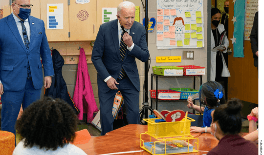 Education Secretary Miguel Cardona watches as President Joe Biden speaks to students in a classroom during a visit to Luis Muñoz Marin Elementary School in Philadelphia, Friday, March 11, 2022.