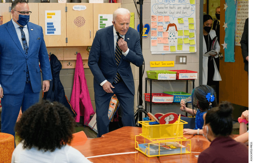 Education Secretary Miguel Cardona watches as President Joe Biden speaks to students in a classroom during a visit to Luis Muñoz Marin Elementary School in Philadelphia, Friday, March 11, 2022.