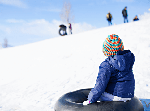 Kid sitting on a tube in the snow
